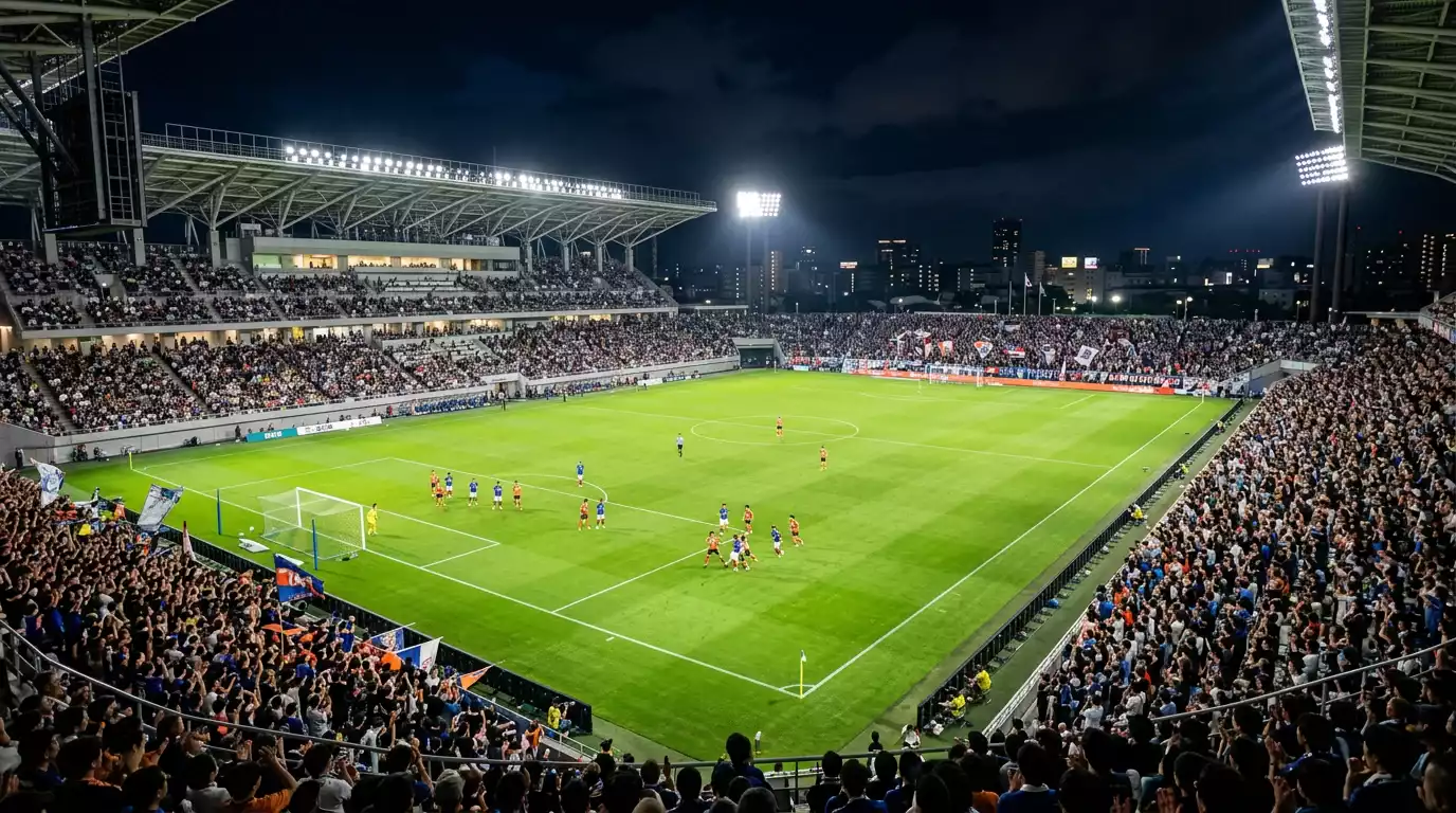 Estadio de la J-League iluminado durante un partido nocturno con las gradas llenas de aficionados
