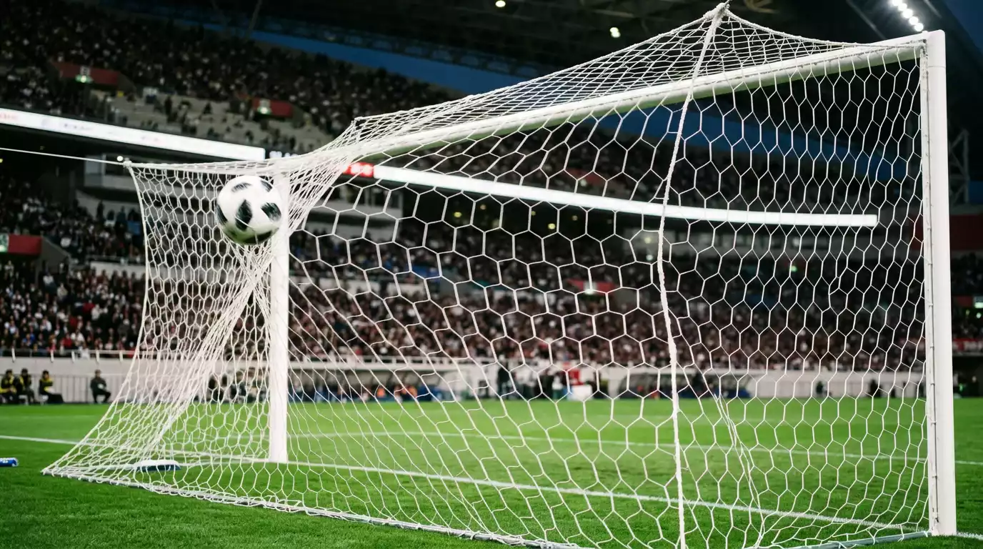 Portería de fútbol con red blanca y balón entrando durante un partido en un estadio japonés