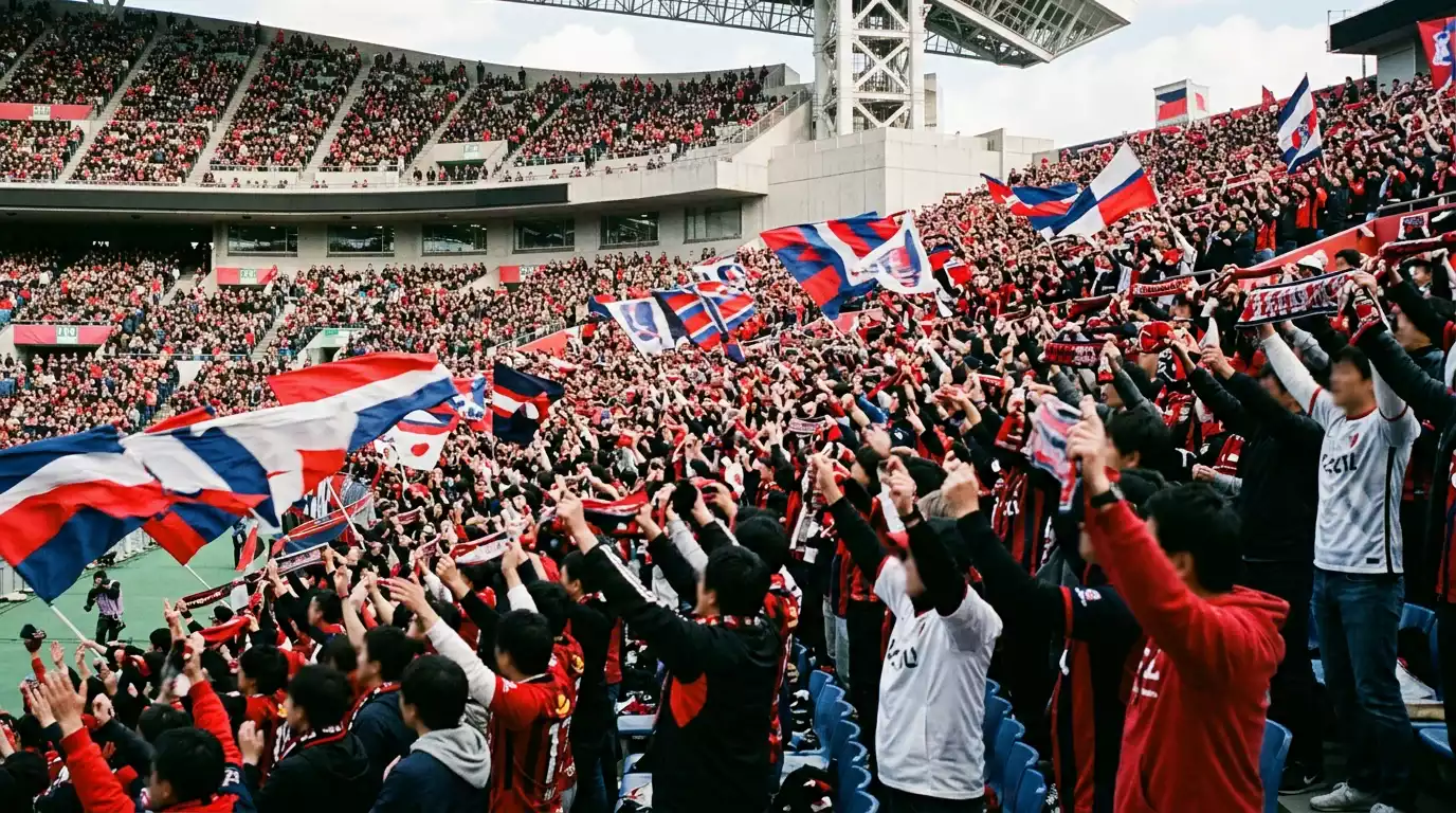Aficionados japoneses animando en las gradas de un estadio de la J-League durante un partido